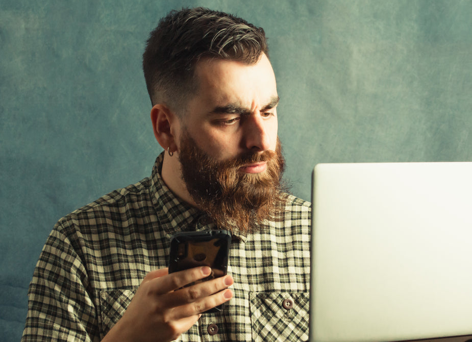 A man in plaid holds a laptop and a cellphone. Photo by Avelino Calvar Martinez from Burst